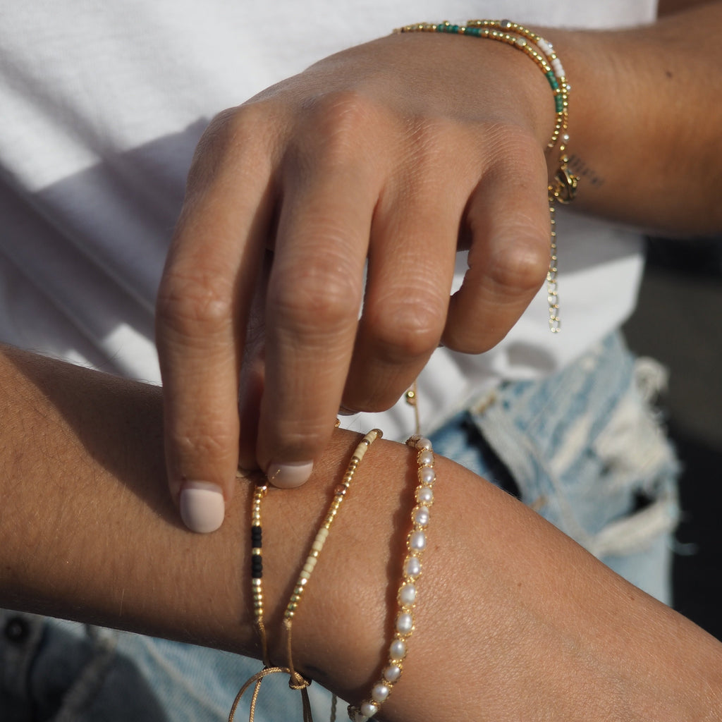 Add a pop of subtle color to your style with our Gleam Beads Adjustable Bracelets. Featuring different colors and gold beads on a silky cotton string, these adjustable bracelets are perfect for layering, with five colors available to create your unique combinations. Lightweight and comfortable, they’re ideal for everyday wear and special occasions alike. Don't forget to check our matchy anklets too!