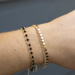 Gold bracelets with black beads and mini disc charms