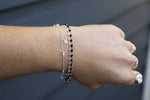 Silver bracelet with black bohemian beads styled with a fine star bracelet